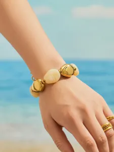 Gros plan détaillé d'un bracelet minimaliste en métal doré et résine sur un poignet.