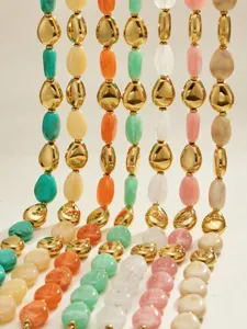 Vue détaillée de chaînes de perles en résine colorée et métal doré, textures élégantes.