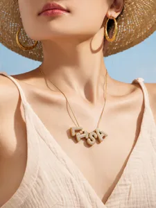 Primer plano detallado de collar con letras de acero inoxidable bañado en oro de 18k y pendientes.