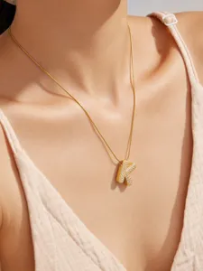 Detalle de cerca de un collar con colgante de letra K bañado en oro con circonitas.