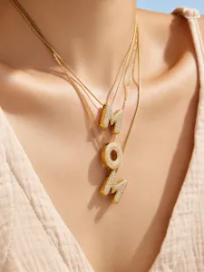 Primer plano detallado de collares con colgantes de letras doradas en capas con circonitas.