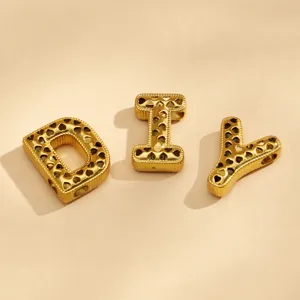 Detalle de dijes de letras DIY dorados, colgante de acero inoxidable bañado en oro 18k corazones.
