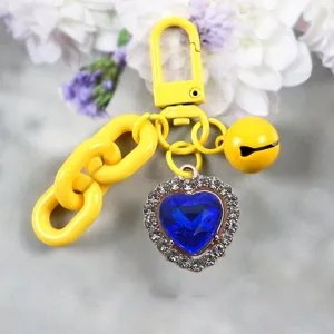 Close-up of the yellow keychain with a sparkling blue heart rhinestone pendant and cute bell.