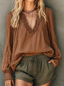 Detailed view of the women's brown long sleeve blouse with elegant V-neck and ruffles.