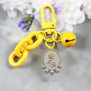 Yellow keychain charm featuring a golden rose oval pendant, cute bell, and pearl accents.