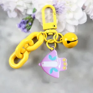 Primo piano dettaglio di un grazioso portachiavi giallo con ciondolo uccellino rosa.
