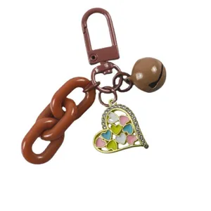 Detailed shot of a brown keychain with chunky chain, bell, and colorful rhinestone heart.