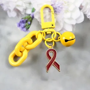 Gele legering sleutelhanger met rode lint hanger, dikke ketting en belbedel, stijlvol tasaccessoire.