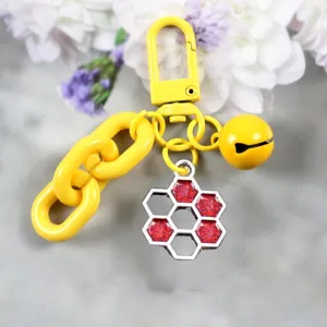Detailed shot of yellow metal keychain with honeycomb pendant and bell, candy color style.