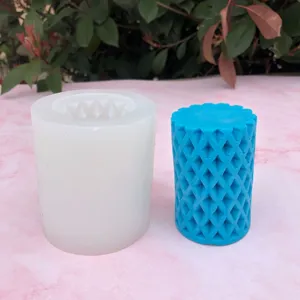 Primo piano di uno stampo per candele cilindrico in silicone con motivo e candela blu.
