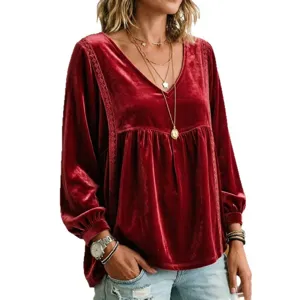 Dettaglio in primo piano della blusa in velluto rosso scuro con maniche lunghe e scollo a V.