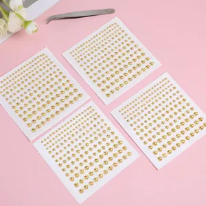 Primer plano detallado de hojas de pegatinas de gemas faciales doradas con pinzas de maquillaje.