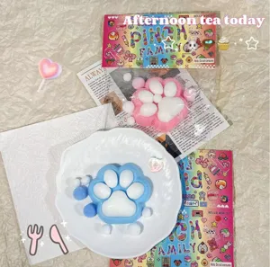 Süße Katzenpfoten-Quetschspielzeuge in Blau und Rosa Plüsch auf einem weißen Dekoteller