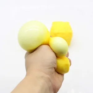 Mano apretando un juguete squishy de cubo de queso amarillo para mostrar el rebote lento