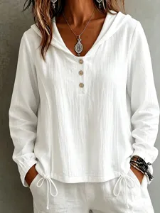 Dettaglio di elegante camicia bianca con cappuccio e maniche lunghe con bottoni.