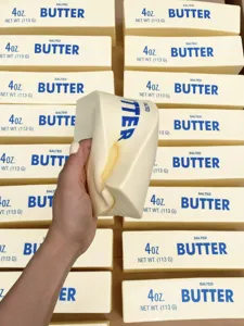 Nahaufnahme einer Hand, die ein realistisches Butterstab-Quetschspielzeug zum Stressabbau drückt