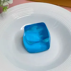 Detaillierte Makroansicht eines lichtdurchlässigen blauen Eiswürfel-Quetschspielzeugs auf Teller