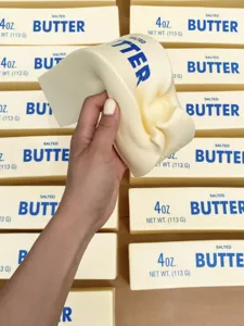 Nahaufnahme eines realistischen Butter-Squishy-Spielzeugs, das gedrückt wird.