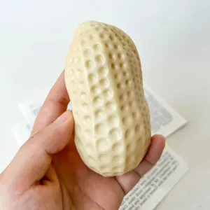 Nahaufnahme eines erdnussförmigen cremefarbenen Squishy-Spielzeugs mit realistischer Textur