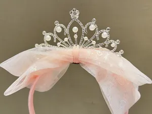 Close-up detail of the sparkling rhinestone pearl crown with delicate pink mesh bow hair accessory.