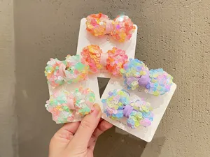 Primo piano dettagliato di mollette per capelli con fiocco in paillettes colorate su cartoncini.