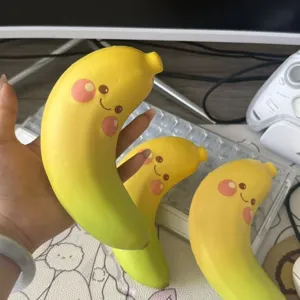 Hand hält ein süßes gelbes Bananen Squishy Spielzeug mit Smile Gesicht zum Stressabbau