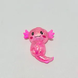 Nahaufnahme eines süßen rosa glitzernden Axolotl-Spielzeugs auf weißem Hintergrund.