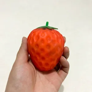 Makro-Detail des roten Erdbeer-Squishy-Spielzeugs in der Hand mit Oberflächenstruktur