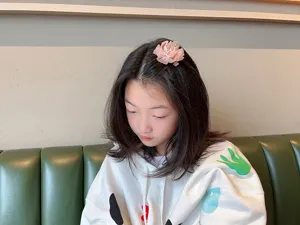 Detailaufnahme einer süßen rosa Netzblumen-Haarspange mit Perlen im Kinderhaar.