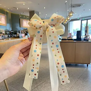 Cute cream white polka dot bow hair clip for girls, sweet ribbon hair accessory detail view.