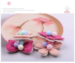 Detailansicht von handgefertigten Kinderhaarteilen mit Stoffblumen und bunten Perlen.