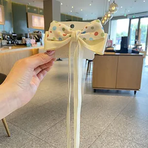 Cute kids hair bow clip with polka dots and long ribbons, sweet cream white design for girls daily wear.