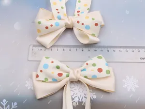 Detail shot of cream white polka dot hair bow ribbon, showing close-up product texture.