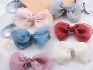 Large organza bow hair clips detail showcasing soft translucent fabric and pastel colors for girls.