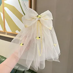 Detailed close-up view of the elegant beige mesh bow hair clip with flowing veil and floral accents.