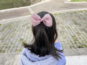 Detail view of a cute pink organza bow hair clip worn on hair, sweet style for daily wear.
