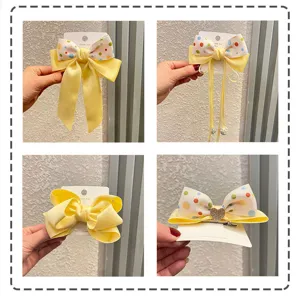 Detailansicht süßer gelber Schleifen-Haarspangen mit Punkten, Bändern und glänzenden Strass-Herzen.