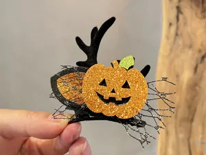 Detailaufnahme der Halloween-Haarspange mit Glitzer-Kürbis und Hirschgeweih für festliche Kostüme.