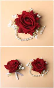 Red rose wrist corsage and boutonniere set with pearls and ribbon for wedding ceremony.
