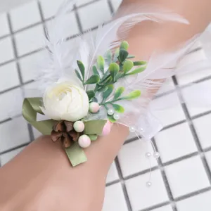 Elegant wedding wrist corsage with white rose, feathers and green leaves for party