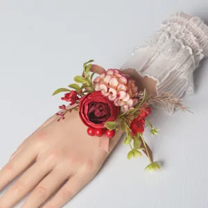 Detailed close-up of artificial wedding wrist flower corsage with red roses and pink hydrangeas.