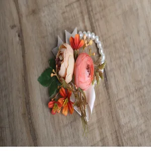 Close-up detail of floral wrist corsage featuring peach roses, green leaves, and pearl bracelet.