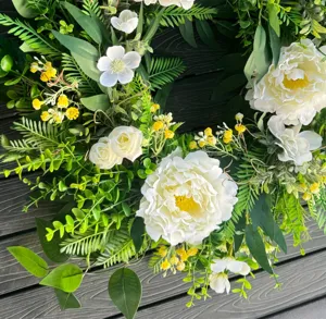 Artificial floral wreath with white peonies, magnolias, and lush green leaves for door decor.