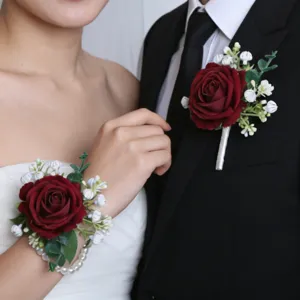 Detalle de botonera de rosa burdeos y corsé de muñeca de perlas para novia y novio de boda.