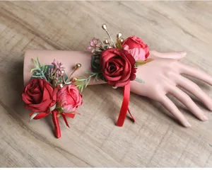 Burgunderrote Hochzeits-Handgelenkskorsage und passender Anstecker mit Rosen und goldenen Beeren.