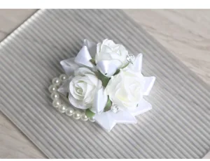 Dettaglio di fiore da polso con rosa artificiale bianca e perle per damigelle di matrimonio.