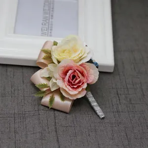 Vista dettagliata della boutonnière di rose artificiali con fiori rosa, bianchi e nastro.