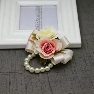 Corsetto da polso di rosa artificiale con bracciale di perle e nastro per festa di nozze.