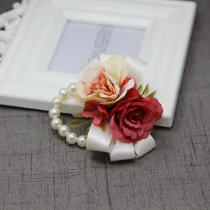 Elegante fiore da polso in rosa artificiale con bracciale di perle e nastro di raso bianco per matrimoni.