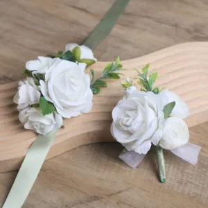 Gros plan détail de l'ensemble boutonnière et fleur de poignet en roses blanches artificielles.